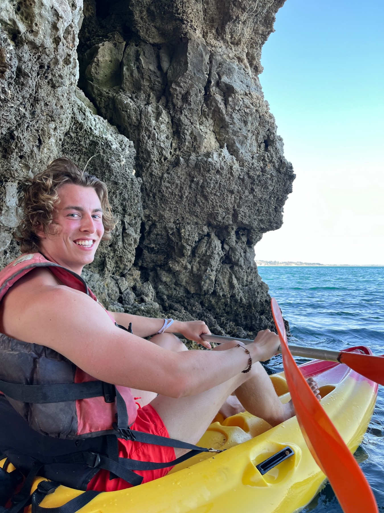 Jack smiling while kayaking beside coastal caves in the Algarve